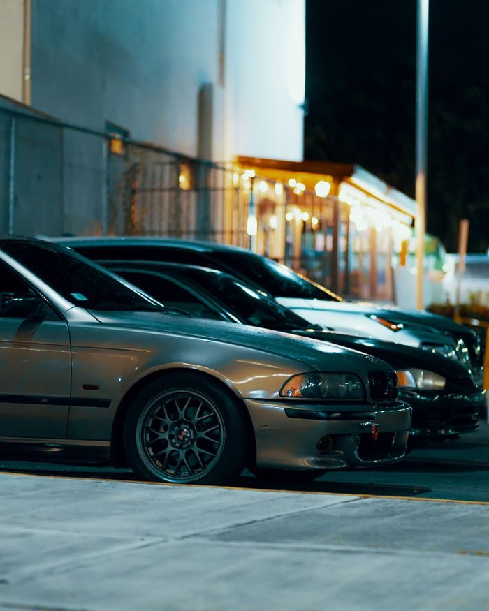 Street scene of parked cars at night in an urban setting with warm lighting.