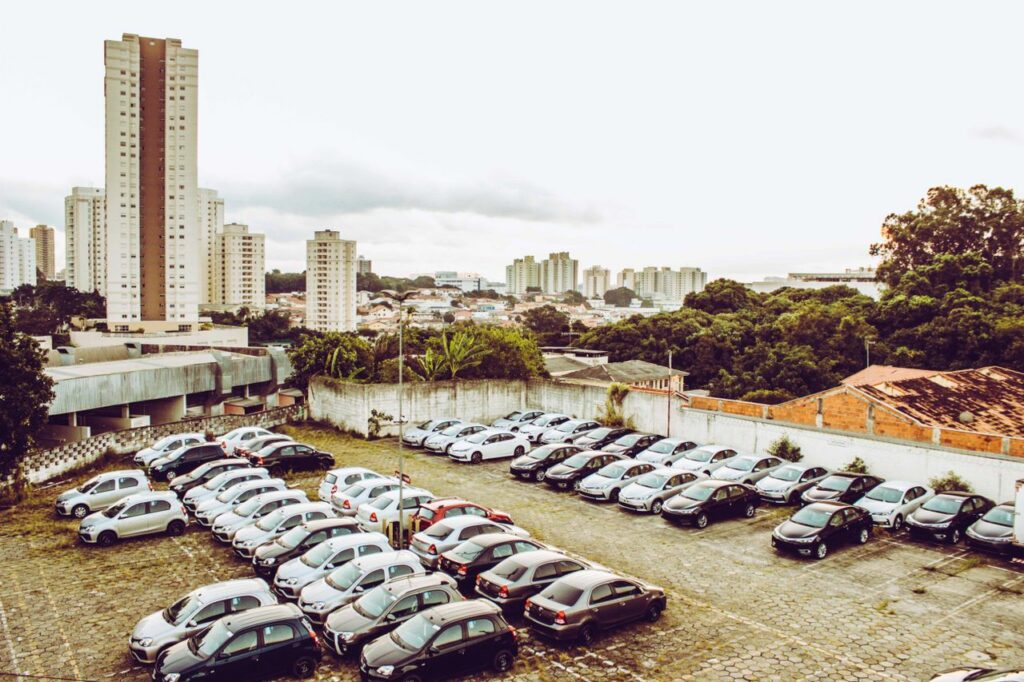 High angle view of cars parked in a city lot with skyline in the background.